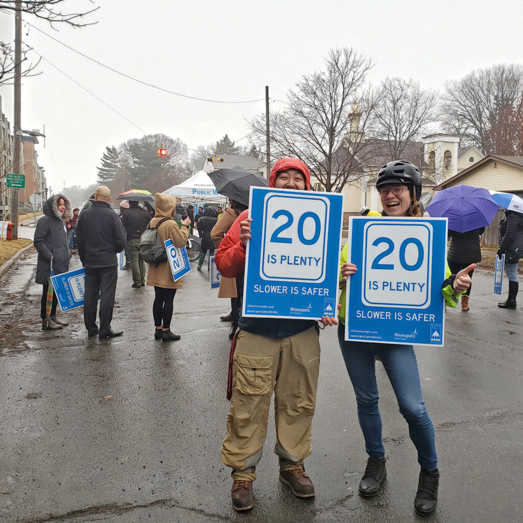 Two smiling people in Minneapolis holding traffic safety signs.