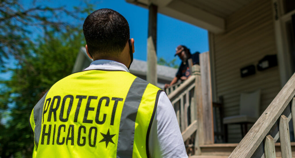 Chicago public health worker approaches a resident standing on her porch