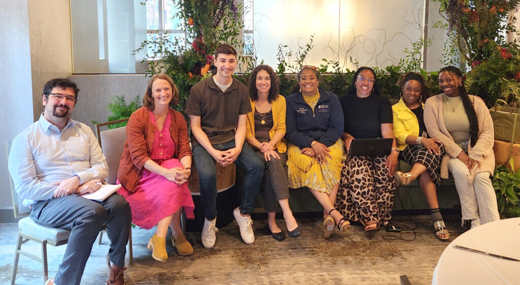 Group of 8 people sitting and smiling