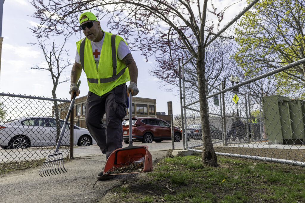 Man rakes trash into a dustpan in a park