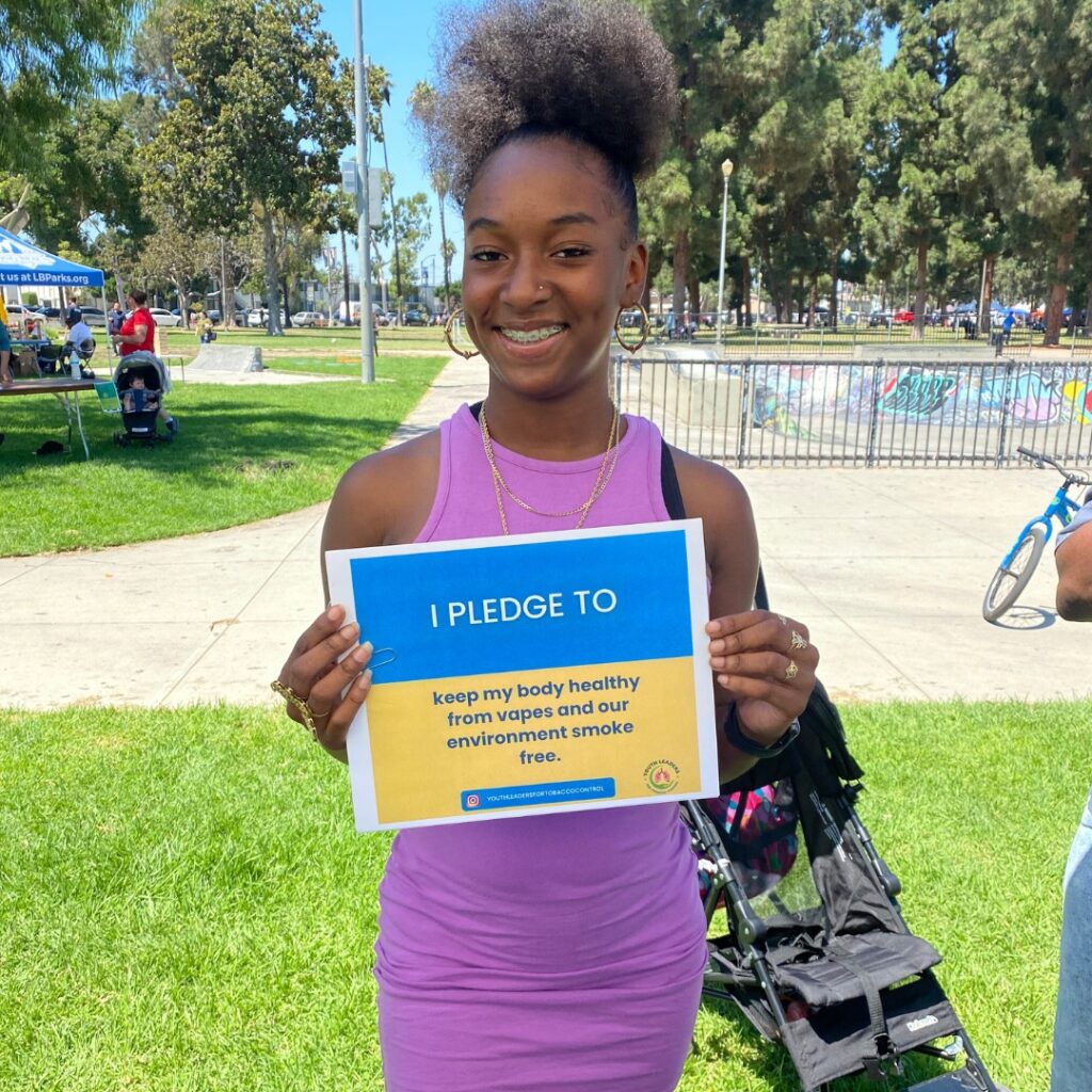 Teenage girl holding sign saying she pledges not to vape