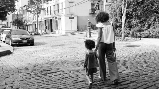 Parent and young child walking down a cobblestone street