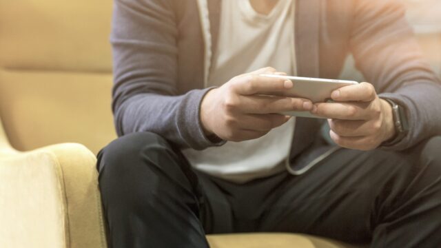 Young man sitting in chair and looking at smartphone. Photo courtesy of LinkedIn Sales Solutions / Unsplash