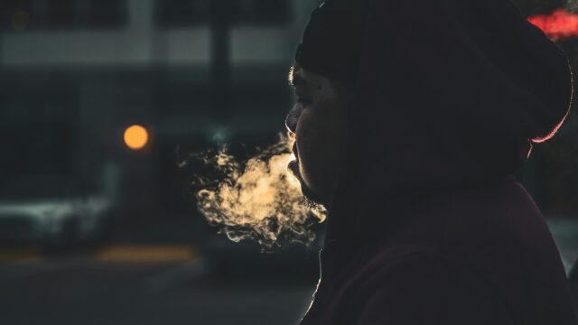 Profile of young man exhaling smoke. Photo by Miguel Gonzelez / Unsplash