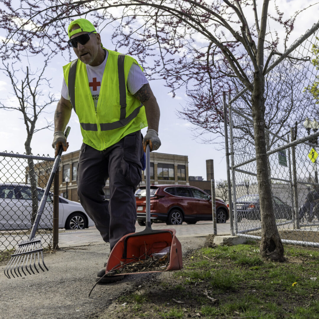 Man rakes trash into a dustpan in a park