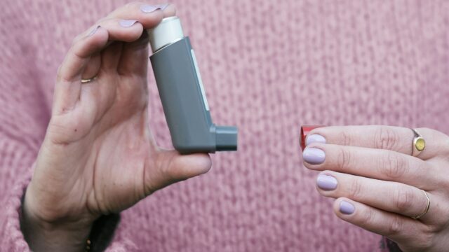 Person in pink sweater holding an asthma pump