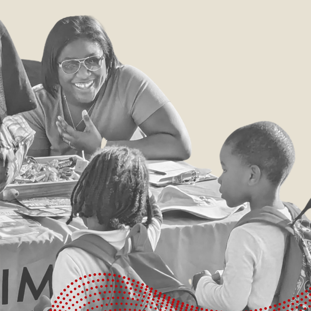 Woman smiling at two schoolchildren who have walked up to her public health table