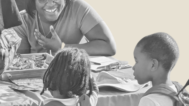 Woman smiling at two schoolchildren who have walked up to her public health table