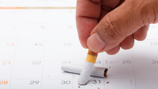 hand putting out a cigarette on a calendar