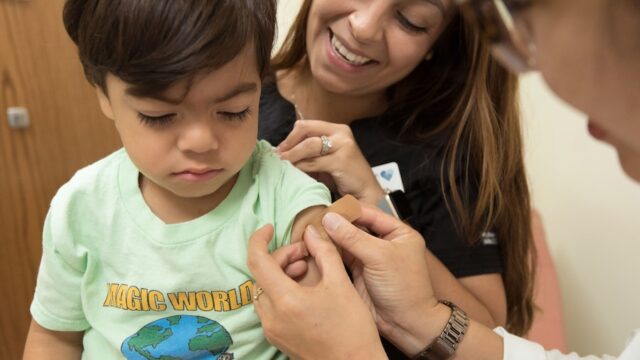 Young boy receiving vaccination while his mother looks on.