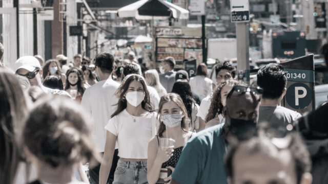 Crowded street in New York City, some people wearing masks and some not. Photo by Yoav Aziz on Unsplash.