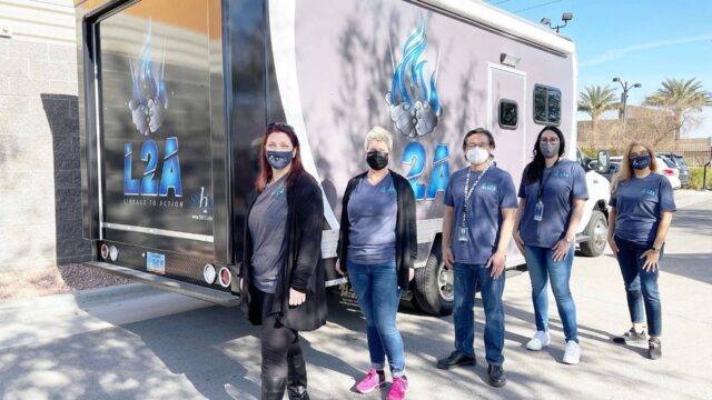 Five public health workers in masks stand in front of a mobile outreach van that reads L2A: Linkage to Action