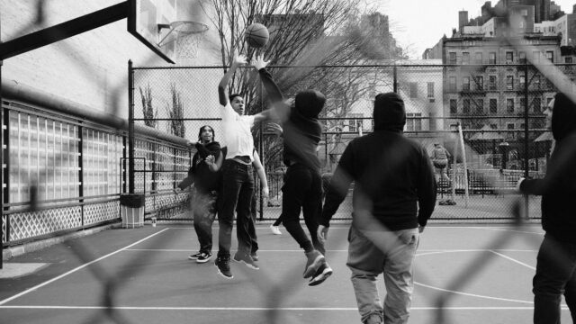 Teenage boys playing basketball at an outdoor court in New York City