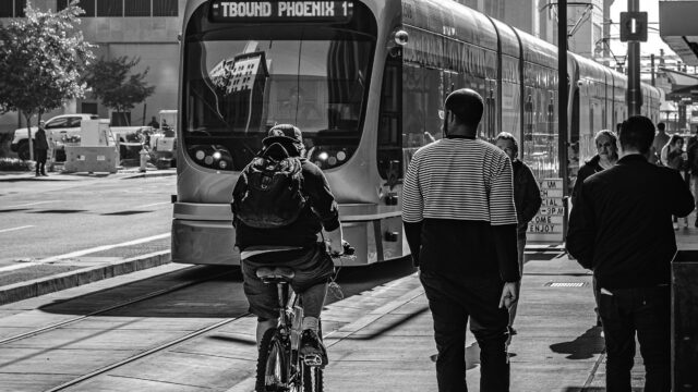 Phoenix downtown scene showing light rail, person on bike, people walking. Photo by Jared Murray on Unsplash.