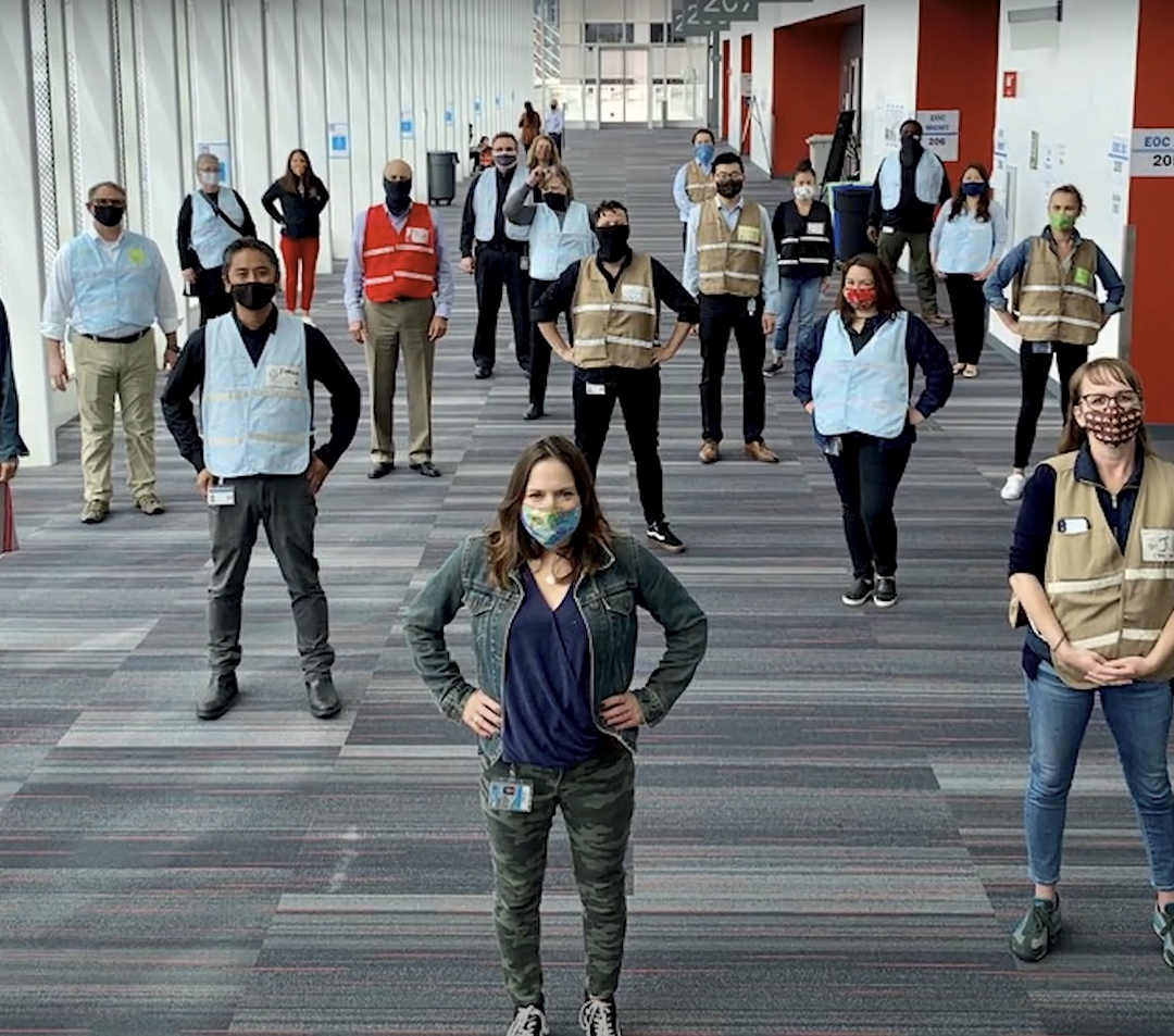 Public health workers, wearing masks, standing 6 feet apart from each other, looking confidently into the camera