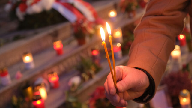 Hand holding candles at a vigil