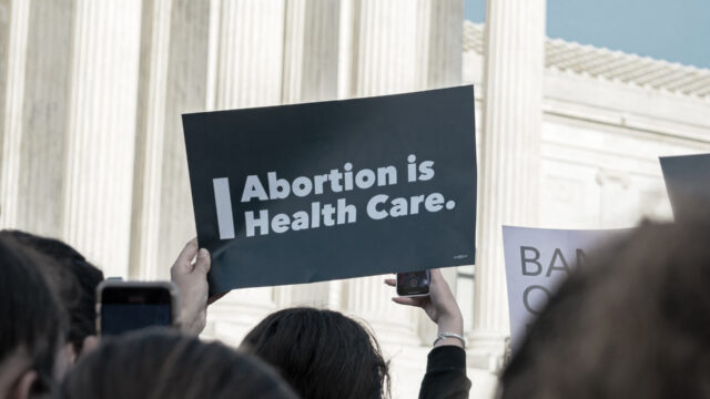 Crowd in front of Supreme Court, woman holding sign that says Abortion is Health Care. Photo by Gayatri Malhotra on Unsplash