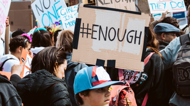 Anti-gun violence protest with child standing in foreground. Photo by Natalie Chaney on Unsplash.